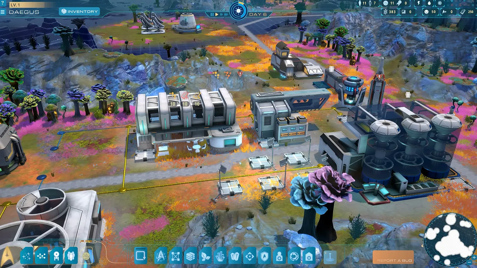 Official gameplay footage of an industrial cluster with rows of grey machines and tall storage tanks, with the build toolbar along the bottom