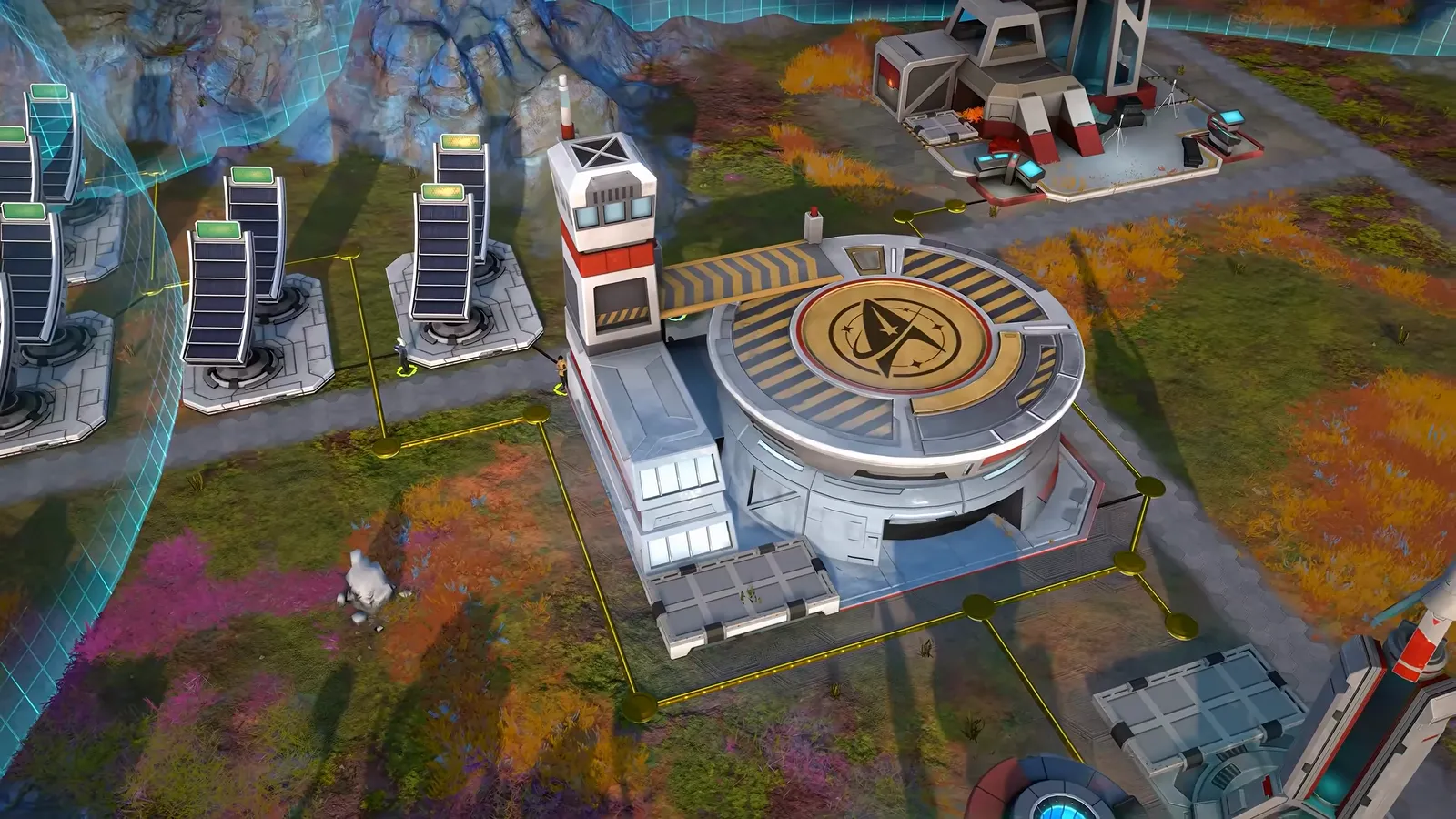 Official gameplay footage of a round building marked with a Starfleet emblem beside a red-and-white tower and rows of tall panel towers, with a yellow line on the ground