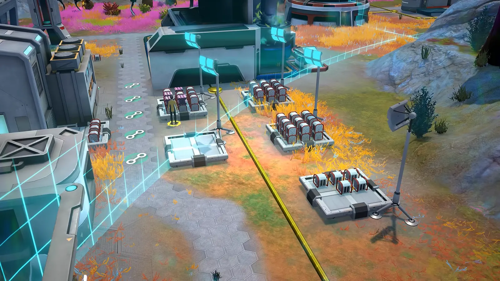 Official gameplay footage of small module clusters and crates on open ground, with a cyan wireframe edge and a yellow line passing between them
